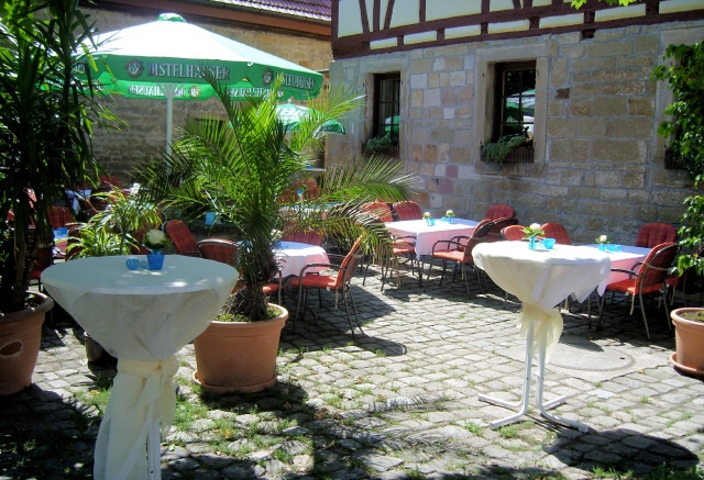 Sommerlicher Biergarten mit eingedeckten Tischen im Innenhof