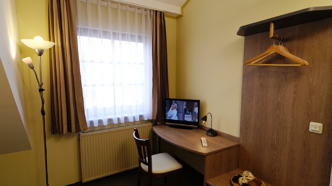 Zimmerdetail mit Schreibtisch, Fernseher und Garderobe