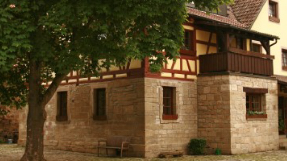 Historisches Sandstein- und Fachwerkgebäude der Mühle unter einem Baum
