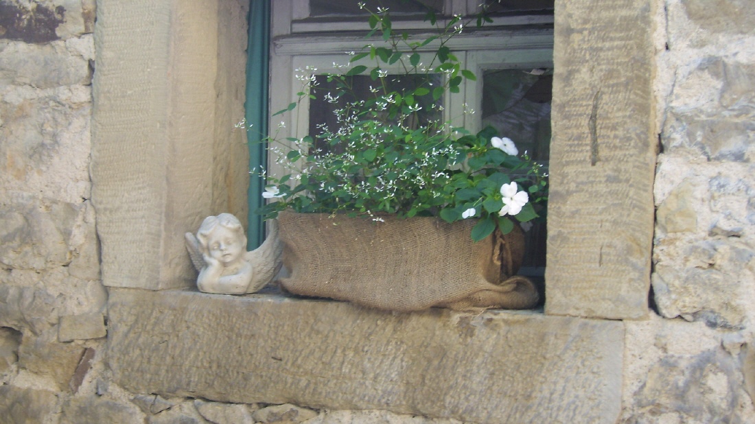 Liebevolles Detail: bepflanztes Sandstein-Fenster mit Engelsfigur